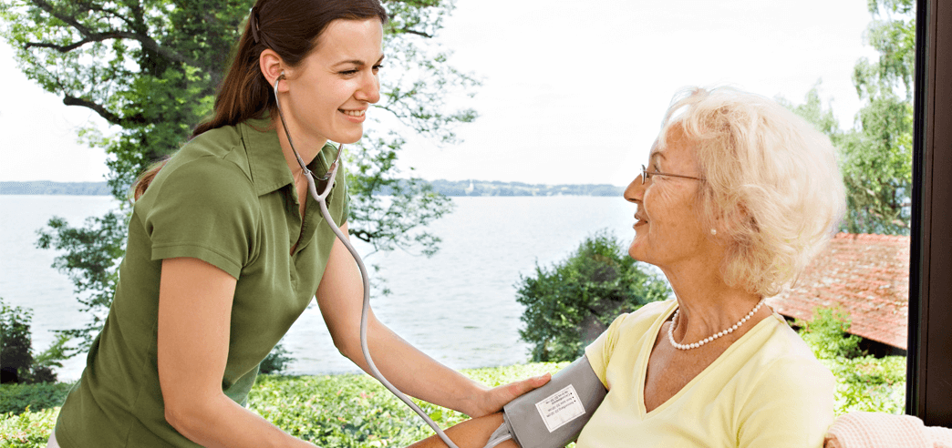 Pflegerin in der Ausbildung misst den Blutdruck einer Seniorin